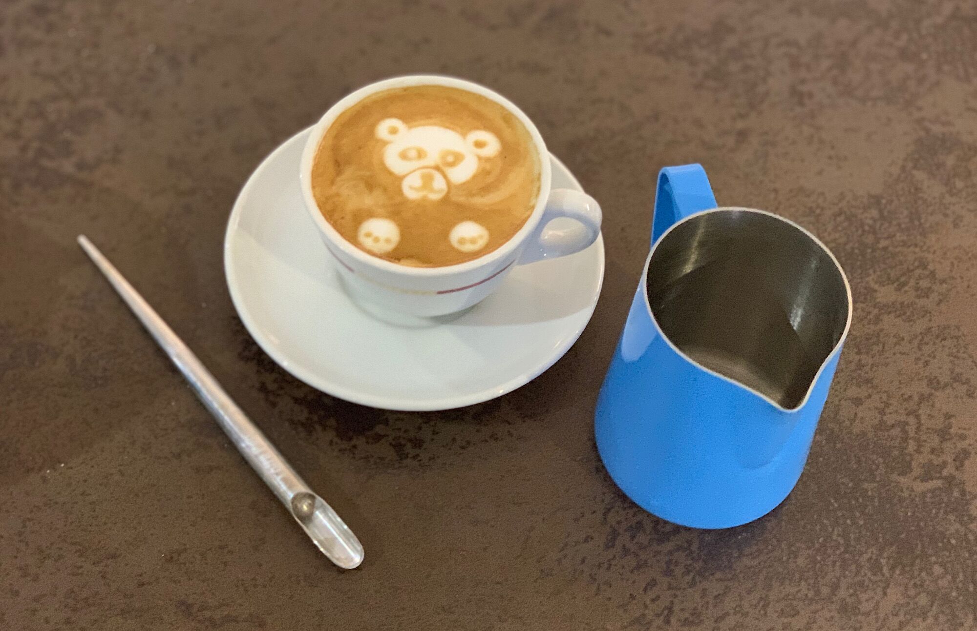 Latte-Art-Bär mit Milchkännchen und Latte-Art-Pen